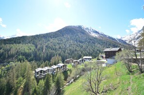 Ein Bergdorf mit Chalets, eingebettet zwischen dichten Wäldern und schneebedeckten Gipfeln.