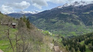 Paisaje montañoso con un valle, casas y una carretera.