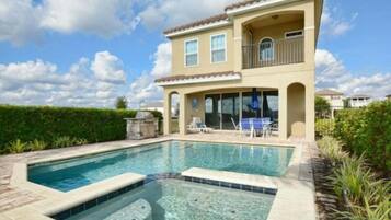 A two-story house with a swimming pool and a patio area.