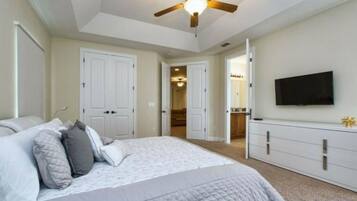 A bedroom with a bed, a ceiling fan, a TV, and a wardrobe.