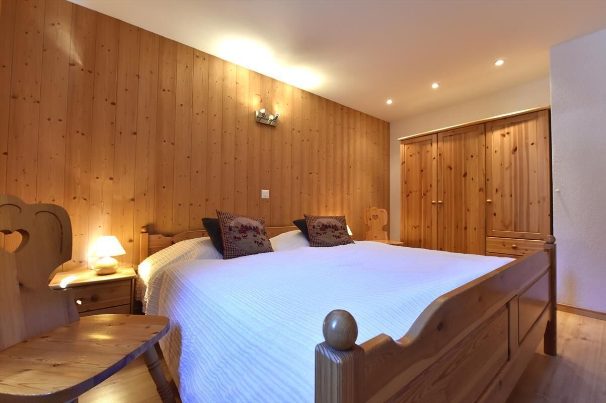 Ein Schlafzimmer mit Holzwandverkleidung, einem großen Bett, Nachttischen und einem Kleiderschrank.