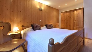 Un dormitorio con paneles de madera, una cama grande, mesitas de noche y un armario.