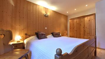 Ein Schlafzimmer mit Holzwandverkleidung, einem großen Bett, Nachttischen und einem Kleiderschrank.