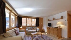 Una sala de estar con sofá, mesa de centro, televisor y mueble.