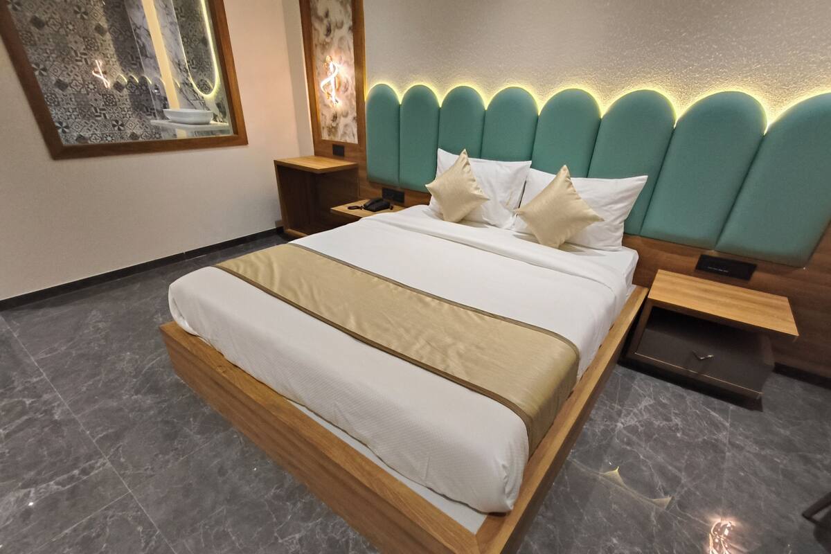 Une chambre moderne avec un grand lit, une tête de lit dotée d’un éclairage intégré, une table de chevet et une commode.