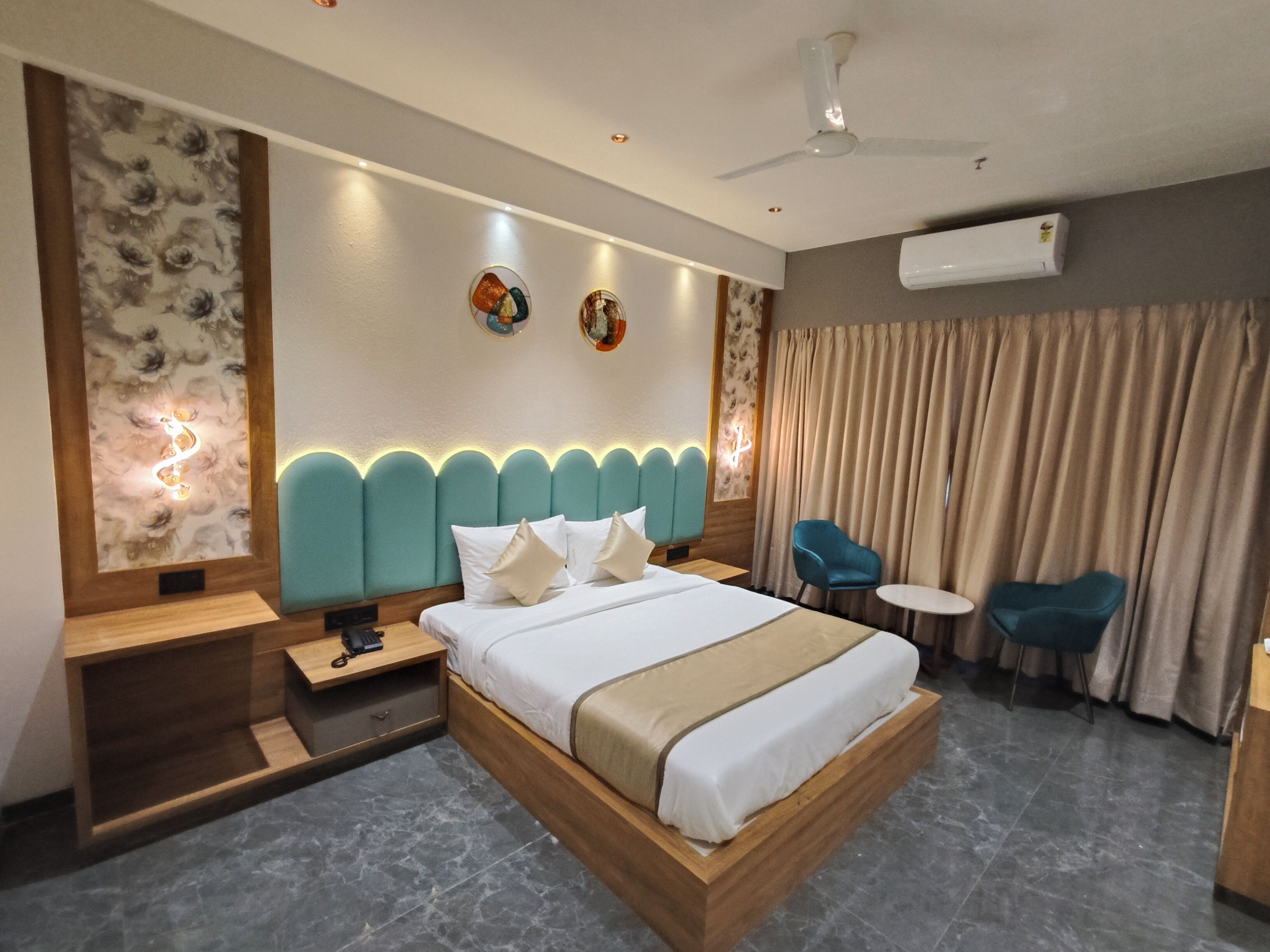 Une chambre d’hôtel moderne avec un grand lit, une table de chevet, un bureau, une chaise et un ventilateur de plafond.