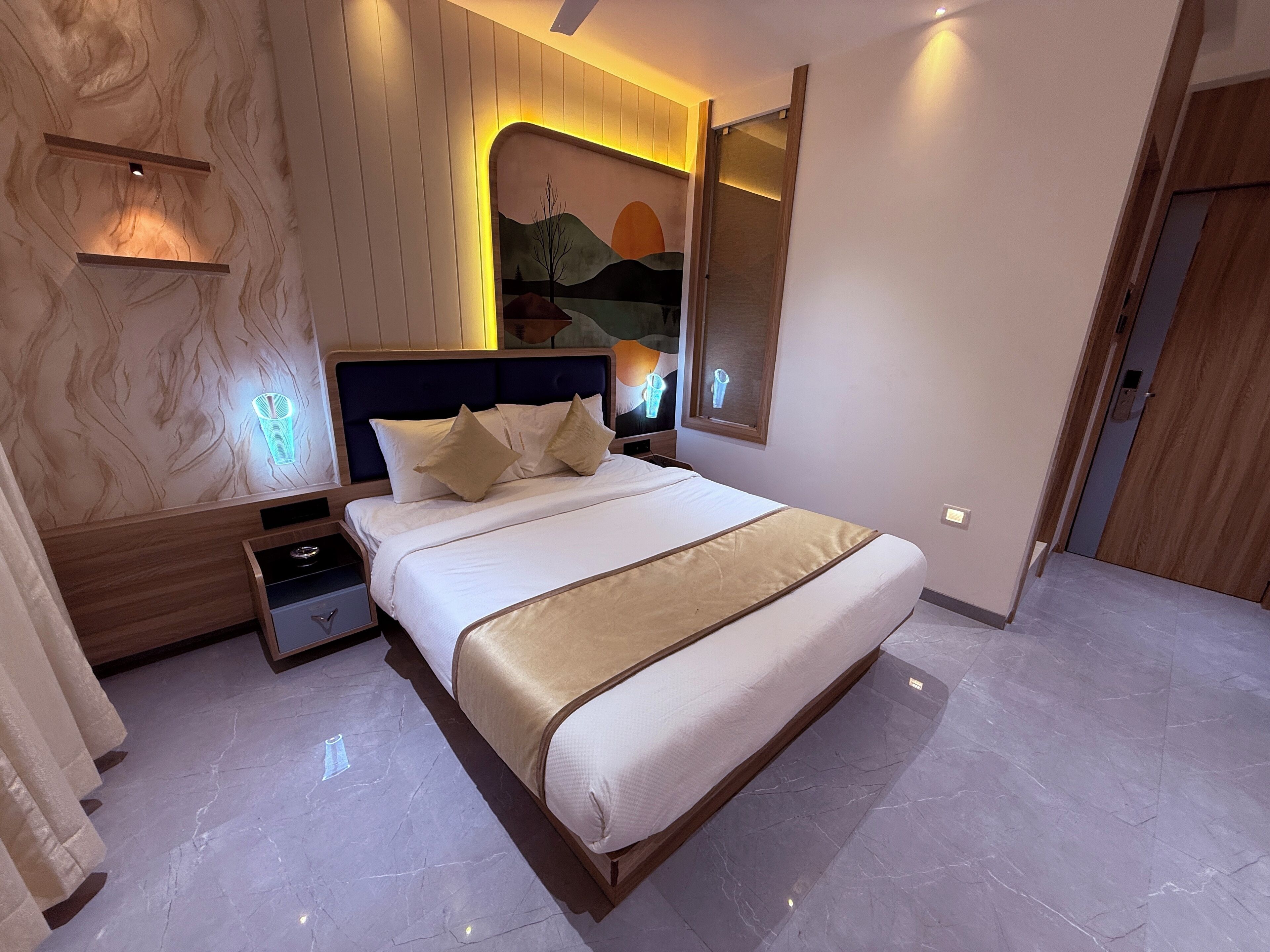 A modern hotel room with a large bed, a nightstand, a wall-mounted TV, and a large mirror.