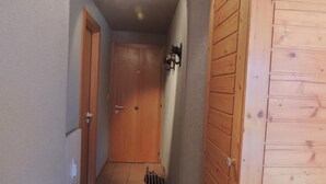 A narrow hallway with wooden doors and a radiator on the left. - 2 room apartment for 2-4 persons : Living room with sofa-bed and 1 pull-down bed - kitchen with dish (Grimentz)