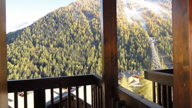 Blick auf Berge vom Balkon mit Holzgeländer.