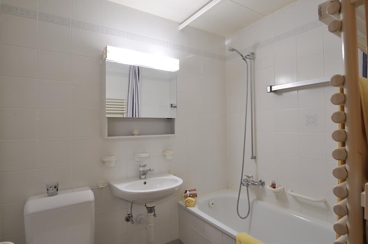 A bathroom with a sink, mirror, toilet, and bathtub.