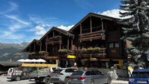 Un bâtiment en bois doté de balcons, un fourgon garé et des voitures.