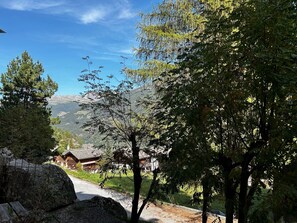 En landlig landsby med traditionelle huse, klar himmel og et bjerglandskab i baggrunden.