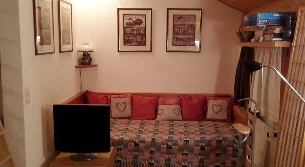 Una camera accogliente con un letto, una televisione, quadri appesi alle pareti e una libreria piena di libri.