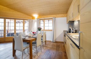 A modern kitchen with wooden cabinets, a dining area with a table and chairs, and large windows with curtains. - Brand new with spa : very comfortable 3 room apartment (2nd floor) for 4-5 persons near the ski lift (Grimentz)