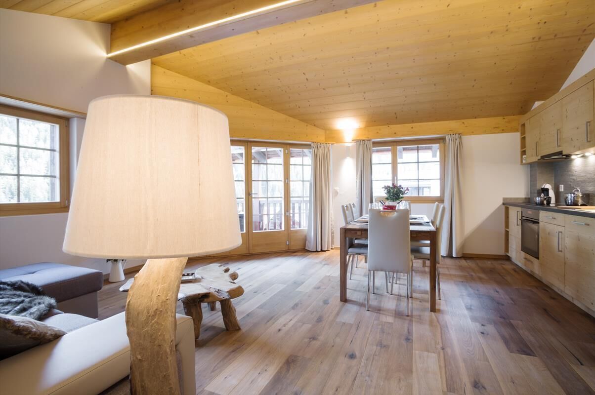 Ein geräumiger Raum mit Holzbalkendecke, einer Essecke mit Tisch und Stühlen sowie einer Küchenzeile mit Schränken und Geräten.