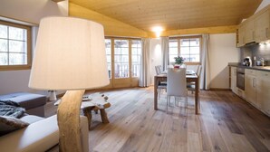 Een ruime kamer met houten plafond, een eethoek met tafel en stoelen, en een keuken met kasten en apparatuur.