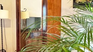 A wooden door with a mirror, a floor lamp, and a potted plant in a room with a wooden ceiling.