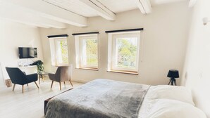 A modern bedroom with a large bed, a desk, and a chair. There are three windows providing natural light. - Studio 5, sous-combles (Rurange-lès-Thionville)