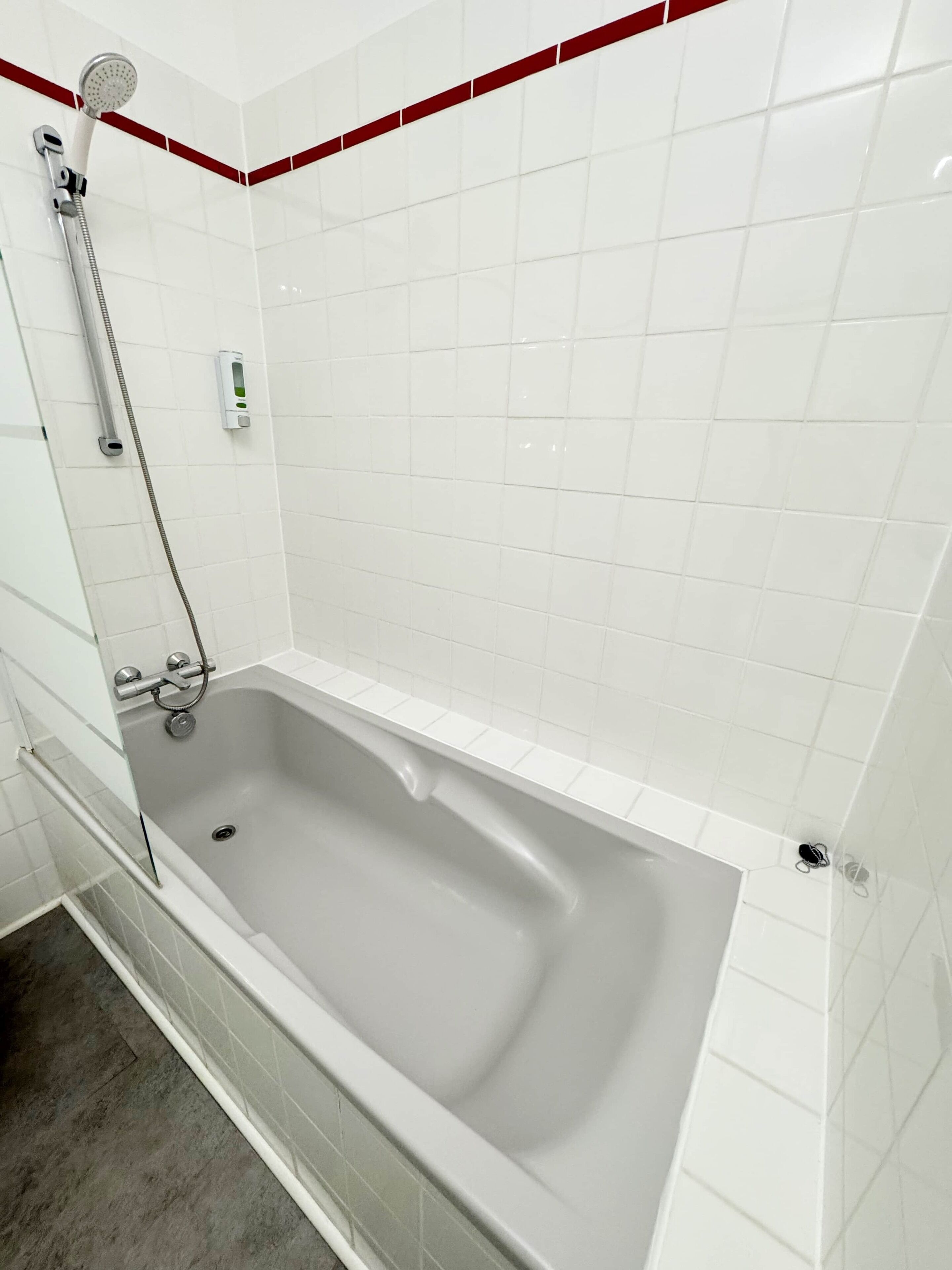 A modern bathroom with a bathtub, a shower, and a hand dryer.