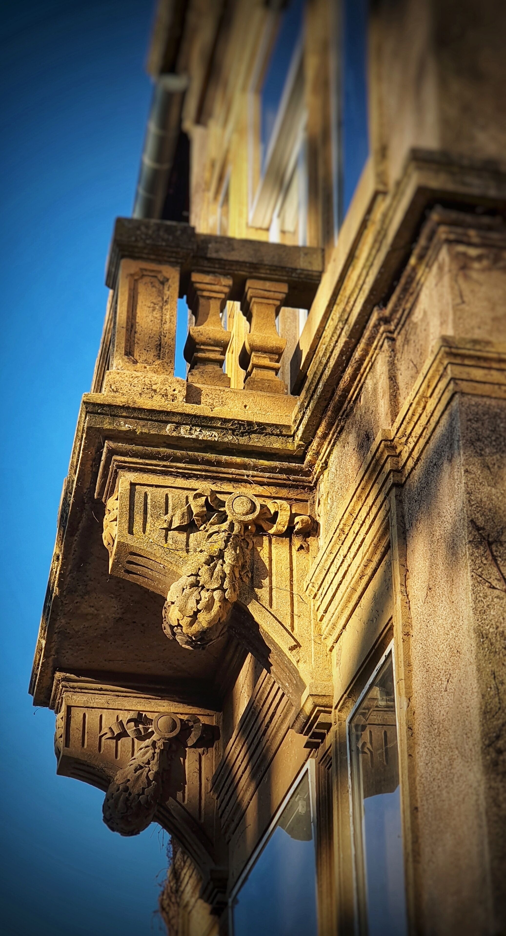 Um primeiro plano do trabalho em pedra ornamentado de um edifício, incluindo um leão de pedra esculpido e molduras arquitetônicas detalhadas.