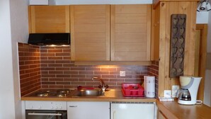 A compact kitchen with a gas stove, a sink, a dishwasher, and wooden cabinets. - Comfortable 2  1/2-room apartment for 4 persons : living room - 1 alcove with 2 bunk beds - 1 room w (Grimentz)