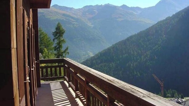 Ein Holzbalkon mit Blick auf ein Gebirge.