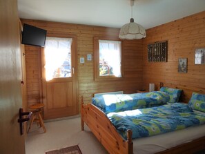 A wooden-paneled bedroom with two beds, a television, and a small stool. - Comfortable chalet for 6 persons : living room with wood stove - kitchen with dish-washer and coffee (Grimentz)