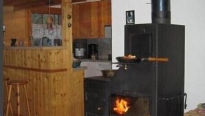 Eine Küche mit Holzofen, Holzschränken und einer Bar.