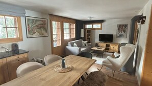 Een ruime woonkamer met een houten eettafel, een bank en een televisie.