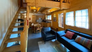 Un interior de madera con una escalera, un sofá, un comedor y una cocina.