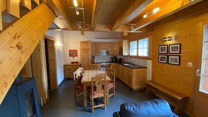 Un interior de cabaña acogedor con comedor, cocina y chimenea.