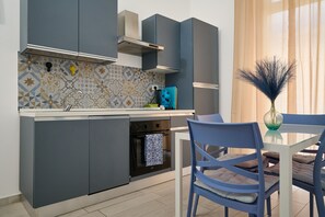 Eine moderne Küche mit grauen Schränken, einem eingebauten Backofen und einem Essbereich mit blauem Stuhl und Tisch.