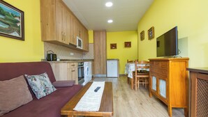 A compact living space with a sofa, a dining table, a kitchen area, and a TV. - Apartments La Huerta de la Torre ( Apartment number 1 ) (Cangas de Onis)