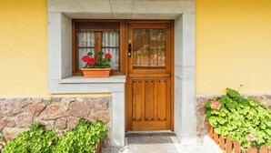 A yellow building with a wooden door, a window with a flower box, and stone walls. - Apartments La Huerta de la Torre ( Apartment number 1 ) (Cangas de Onis)