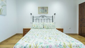 A bedroom with a floral bedspread, a metal headboard, bedside tables, and a wooden door. - Apartments La Huerta de la Torre ( Apartment number 1 ) (Cangas de Onis)
