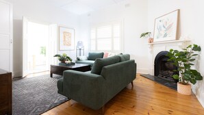 Ein Wohnzimmer mit einem grünen Sofa, einem Kamin und einer Topfpflanze.