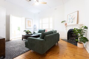 Ein Wohnzimmer mit einem grünen Sofa, einem Kamin und einer Topfpflanze.