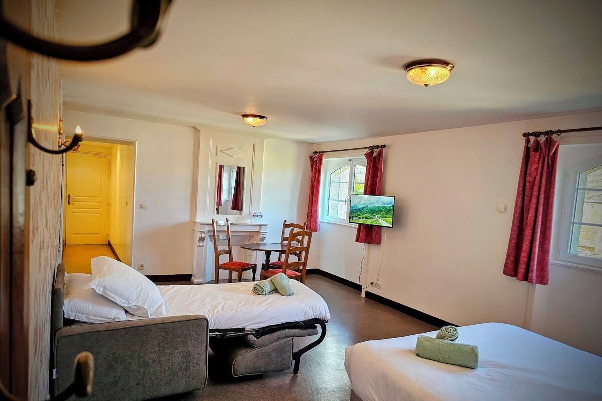 Une chambre d’hôtel avec deux lits, un bureau, des chaises, une télévision et une fenêtre avec des rideaux.
