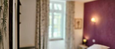 A hotel room with a bed, a nightstand, and a window with curtains.