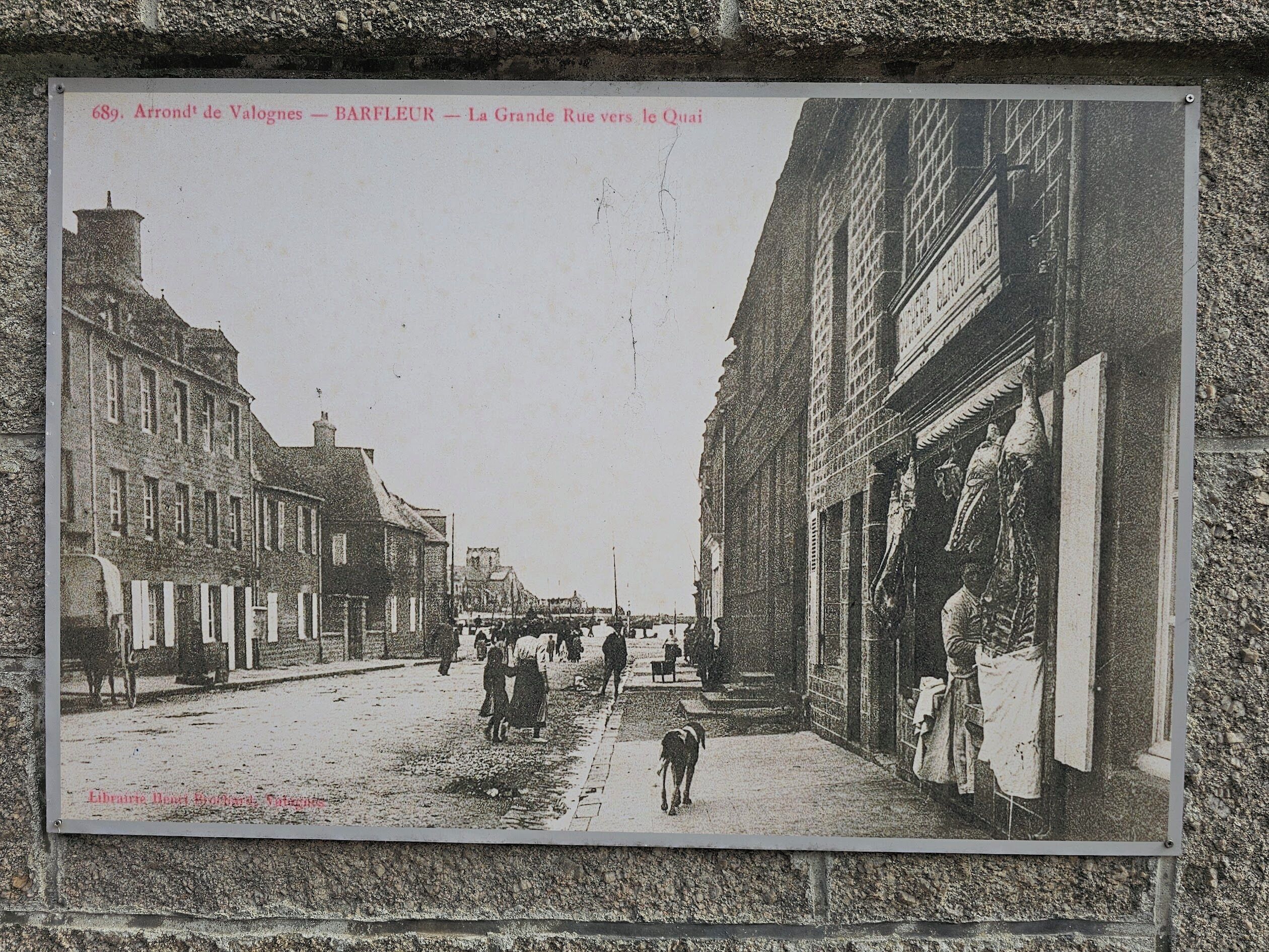 Escena histórica de una calle con edificios, gente y un perro.