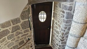 A stone staircase leading to a wooden door with a circular window. - Le Conquérant (Barfleur)