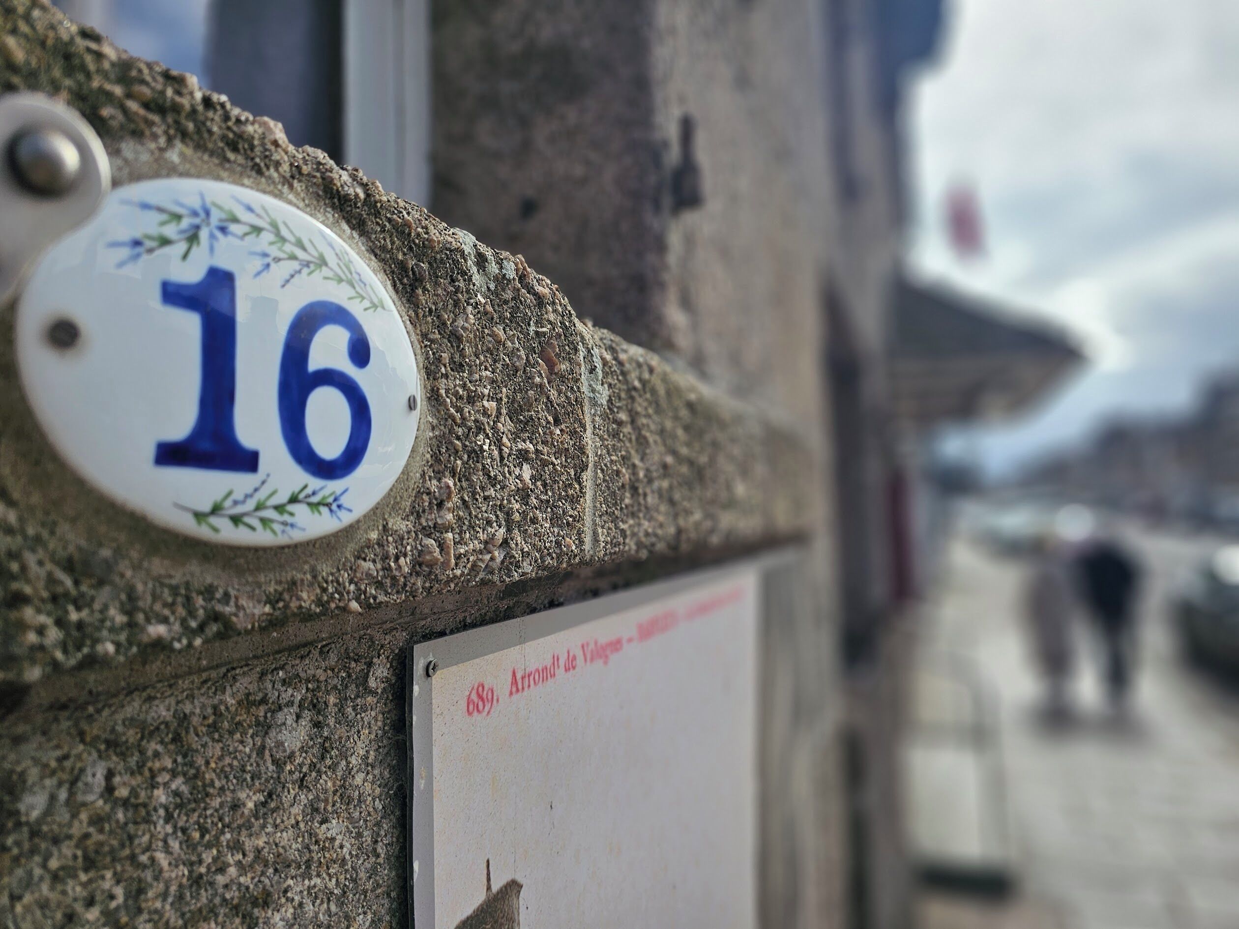 A building corner with a house number plaque '16' and a sign '689, Arrondit de Vauguillon'.