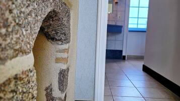 Un couloir avec un mur en pierre et un sol carrelé.