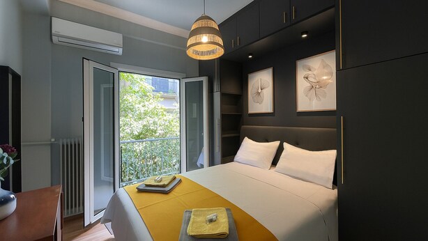 Ein modernes Schlafzimmer mit Bett, Nachttischen, einer Pendelleuchte und Kunstwerken an der Wand.