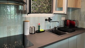 Eine moderne Küche mit eingebautem Herd, einem Fenster mit Pflanze und einem roten Toaster.
