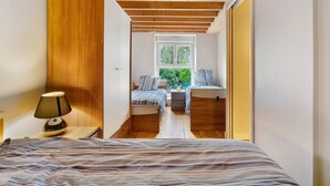 A bedroom with a bed, bedside tables, a window, and a view of greenery outside.