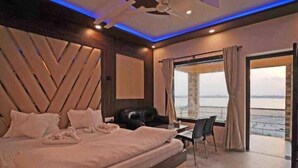 A modern hotel room with a large bed, a desk, and a view of the water. - HYAT LUXURY (Mandarmani)