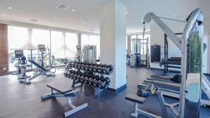 Un gimnasio moderno con diverso equipo de ejercicio, ventanas amplias y un diseño limpio y espacioso.