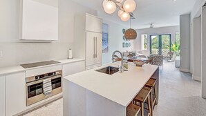 Una cocina moderna con una isla central, horno empotrado e iluminación colgante.