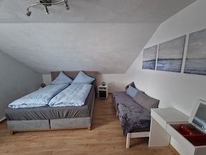 Ett sovrum med en säng, ett nattduksbord, ett TV-bord och konstverk på väggen.